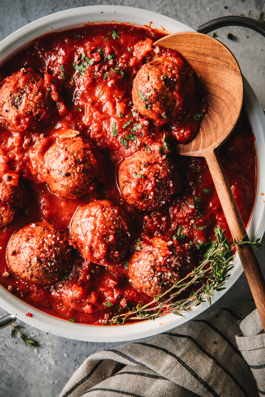 Vegane Meatballs in Tomatensauce Pfanne mit veganen Meatballs und Tomatensauce plus Holzlöffel