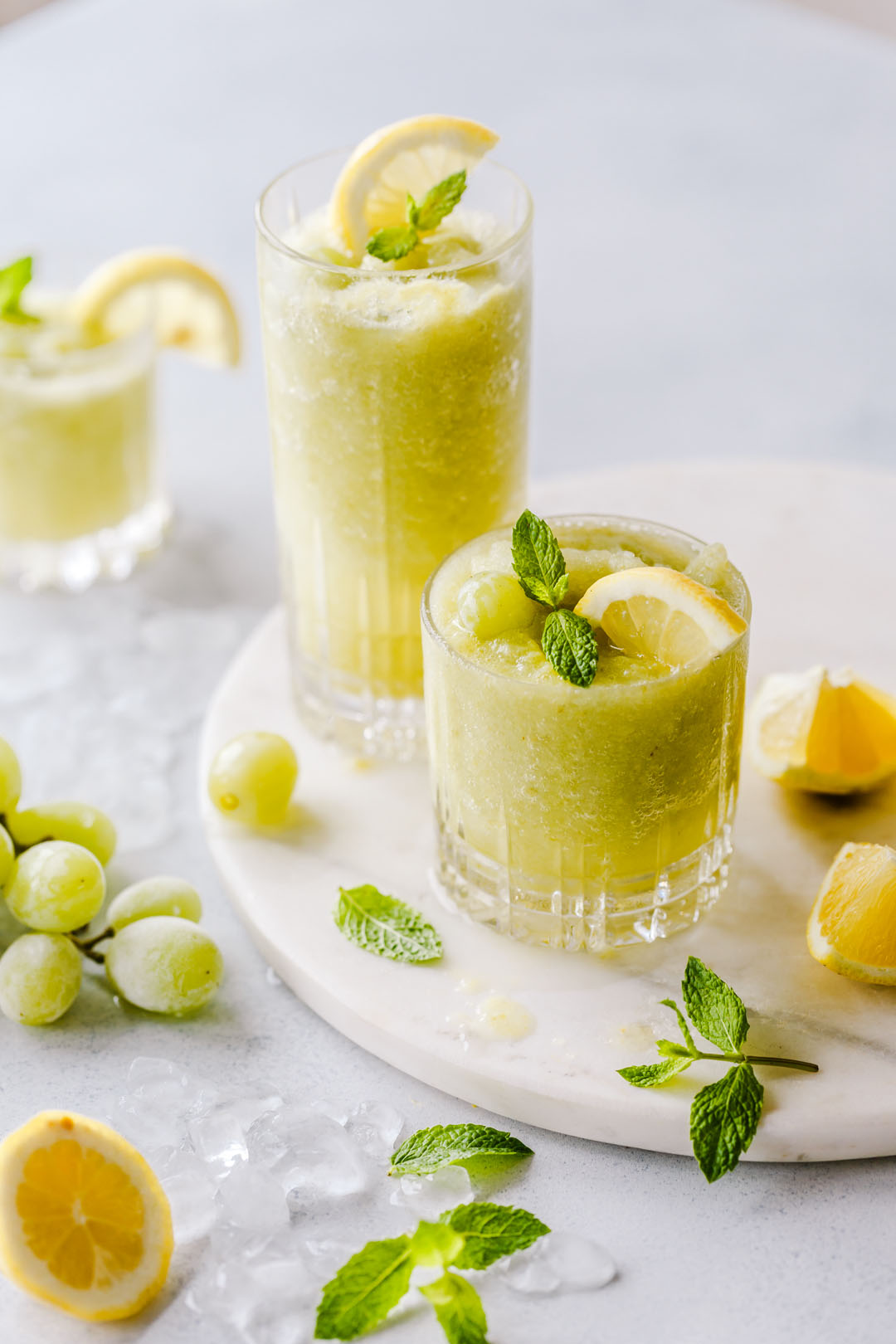 Zwei Gläser gefrorene Limonade auf Marmorplatte mit Trauben und Zitronen