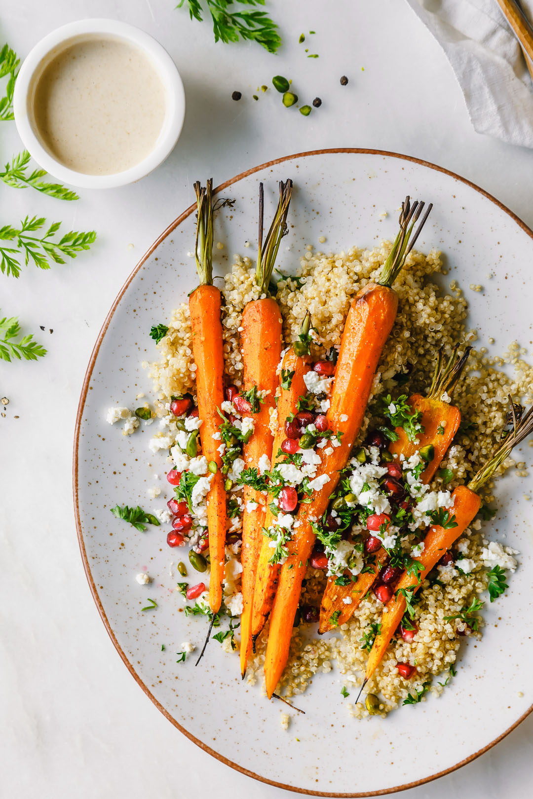 Versteckte Kohlenhydrate in Möhren und Quinoa Gegrillte Möhren auf Quinoa auf grauem Teller auf Tisch