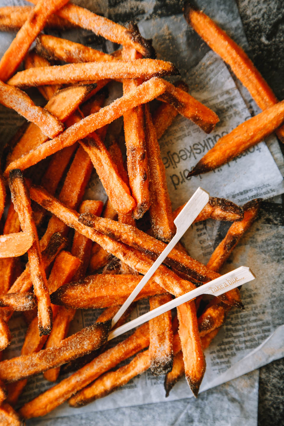 Süßkartoffel-Pommes aus Vorräten Süßkartoffel-Pommes mit zwei Spießen auf Zeitung
