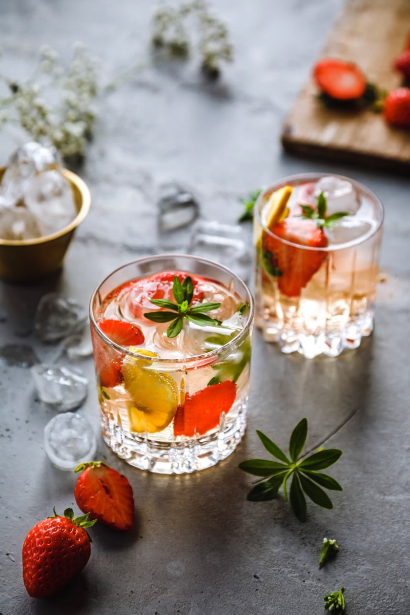 Alkoholfreie Maibowle in zwei Gläsern und Erdbeeren sowie Eiswürfeln