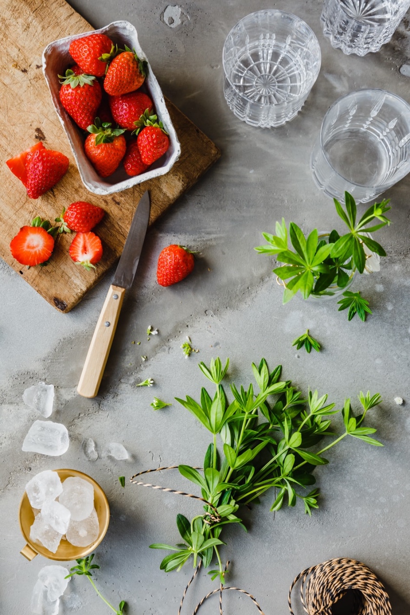 Erdbeeren, Waldmeister, Eiswürfel und Gläser für alkoholfreie Maibowle