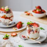 Zwei Gläser veganes Erdbeer-Tiramisu auf Tellern angerichtet