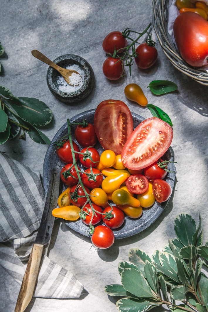 Teller mit verschiedenen Tomatensorten sowie Kräuter